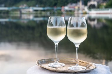 Mosel şarap bölgesinde beyaz kaliteli riesling şarabı tatmak için Mosel nehri ve Almanya 'nın güneşli günlerinde arka planda kalan eski Alman kasabası ile birlikte açık havada servis edilir.