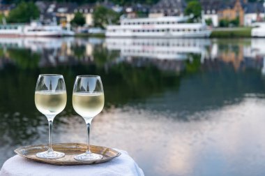 Mosel şarap bölgesinde beyaz kaliteli riesling şarabı tatmak için Mosel nehri ve Almanya 'nın güneşli günlerinde arka planda kalan eski Alman kasabası ile birlikte açık havada servis edilir.