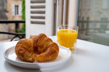 Fransız kahvaltısı, taze kruvasan tereyağlı pasta arkaplanda lezzetli portakal suyu ve eski Fransız evleriyle servis ediliyor.