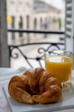 Fransız kahvaltısı, taze kruvasan tereyağlı pasta arkaplanda lezzetli portakal suyu ve eski Fransız evleriyle servis ediliyor.
