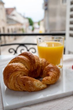 Fransız kahvaltısı, taze kruvasan tereyağlı pasta arkaplanda lezzetli portakal suyu ve eski Fransız evleriyle servis ediliyor.