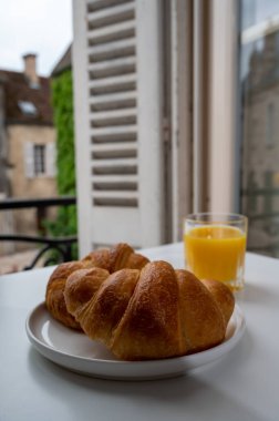 Fransız kahvaltısı, taze kruvasan tereyağlı pasta arkaplanda lezzetli portakal suyu ve eski Fransız evleriyle servis ediliyor.