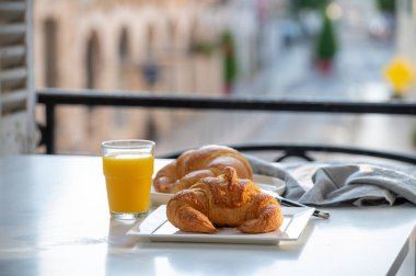 Fransız kahvaltısı, taze kruvasan tereyağlı pasta arkaplanda lezzetli portakal suyu ve eski Fransız evleriyle servis ediliyor.