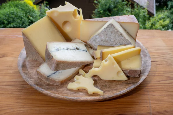 チーズコレクション フランスチーズ付きの木製ボードは 背景に夏にオートサヴォワの夏に来る 美しさ 豊かさ モルビエとフランスの山の村 — ストック写真