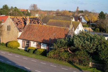 Scharendijke 'de yürürken, Hollanda' nın Zealand şehrinde eski evleri ve Grevelingenmeer 'in mavi sularıyla küçük bir kasaba manzarası var.