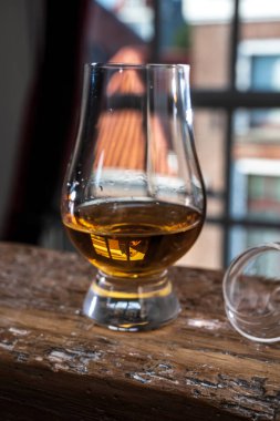 Tek malt viski bardağında servis edilen viski bardağı, eski pencere manzaralı ve ahşap kirişli evler.