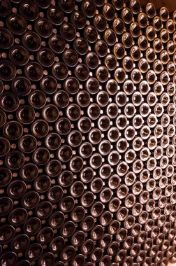 Derin ve uzun yeraltı mağaralarındaki raflarda şişeler şarap ve üzüm şarabından şampanya yapıyor Reims, Champagne, France 'ta.