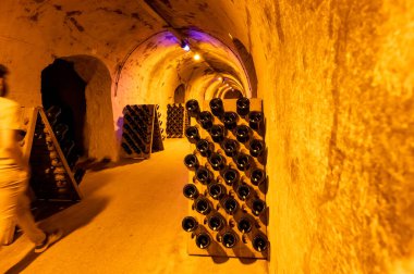 Derin ve uzun yeraltı mağaralarındaki raflarda şişeler şarap ve üzüm şarabından şampanya yapıyor Reims, Champagne, France 'ta.