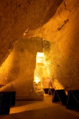 Derin ve uzun yeraltı mağaralarındaki raflarda şişeler şarap ve üzüm şarabından şampanya yapıyor Reims, Champagne, France 'ta.