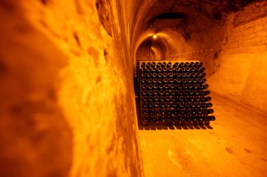 Derin ve uzun yeraltı mağaralarındaki raflarda şişeler şarap ve üzüm şarabından şampanya yapıyor Reims, Champagne, France 'ta.