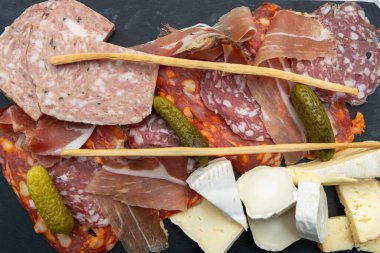 Siyah taş tahtada servis edilen et ve peynir çeşitleri