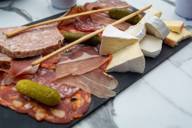 Siyah taş tahtada servis edilen et ve peynir çeşitleri