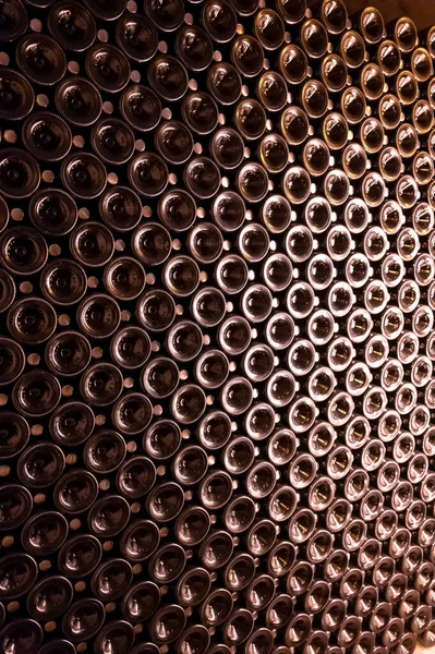 Derin ve uzun yeraltı mağaralarındaki raflarda şişeler şarap ve üzüm şarabından şampanya yapıyor Reims, Champagne, France 'ta.