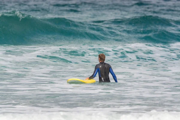 Unidentified surfers train in cold water of Atlantic ocean on famous surf Famara beach, Lanzarote, Canary islands, Spain