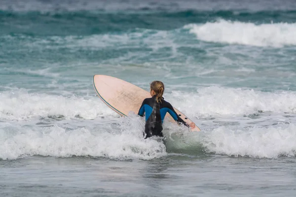 Unidentified surfers train in cold water of Atlantic ocean on famous surf Famara beach, Lanzarote, Canary islands, Spain