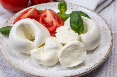 Güney İtalyan yumuşak beyaz mozzarella peyniri bufalo ineklerinden yapılmış taze domates ve taze yeşil fesleğenle servis edilen süt yakın mesafede.