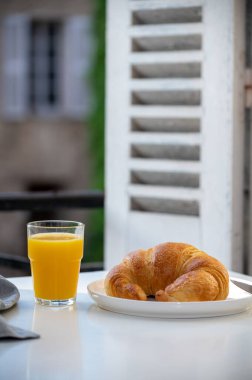Fransız kahvaltısı, taze kruvasan tereyağlı pasta arkaplanda lezzetli portakal suyu ve eski Fransız evleriyle servis ediliyor.