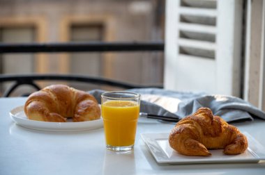 Fransız kahvaltısı, taze kruvasan tereyağlı pasta arkaplanda lezzetli portakal suyu ve eski Fransız evleriyle servis ediliyor.