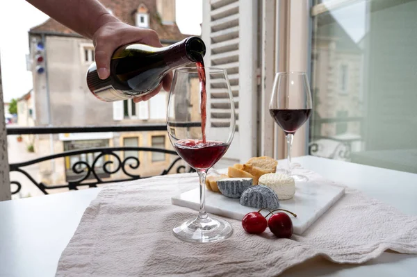 Tasting of burgundy red wine from grand cru pinot noir  vineyards with french goat cheeses and view on old town street in Burgundy Cote de Nuit wine region, France