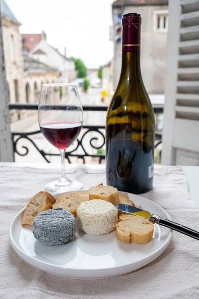 Tasting of burgundy red wine from grand cru pinot noir  vineyards with french goat cheeses and view on old town street in Burgundy Cote de Nuit wine region, France