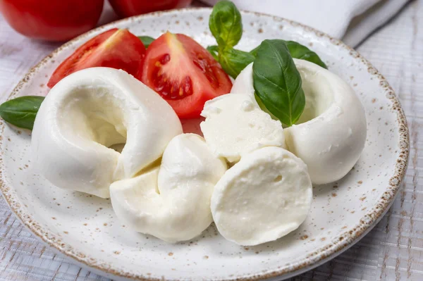 Güney İtalyan yumuşak beyaz mozzarella peyniri bufalo ineklerinden yapılmış taze domates ve taze yeşil fesleğenle servis edilen süt yakın mesafede.