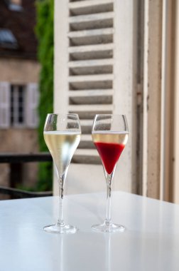 Kir Royal içen, Fransız aperatifi. Krema ve şampanyayla kaplanmış, genellikle flüt bardaklarıyla servis edilen, eski Fransız köyü manzaralı.