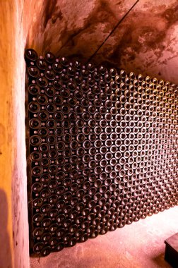 Derin ve uzun yeraltı mağaralarındaki raflarda şişeler şarap ve üzüm şarabından şampanya yapıyor Reims, Champagne, France 'ta.