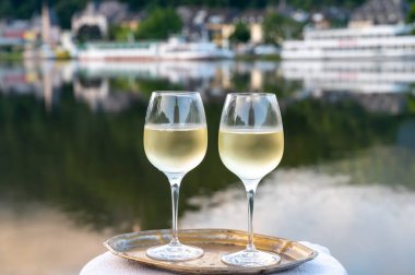 Mosel şarap bölgesinde beyaz kaliteli riesling şarabı tatmak için Mosel nehri ve Almanya 'nın güneşli günlerinde arka planda kalan eski Alman kasabası ile birlikte açık havada servis edilir.