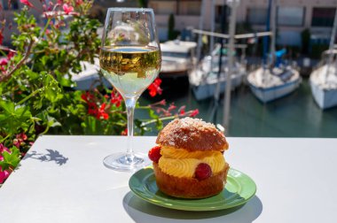 Tarte tropezienne ya da La Tarte de Saint-Tropez. Açık havada servis edilen kremalı ve taze meyveli çöreklerden oluşan tatlı tatlısı. Bir kadeh beyaz şarapla.