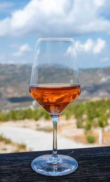 Wine industry of Cyprus island, tasting of rose dry wine on winery with view on vineyards and south slopes of Troodos mountain range in sunny day