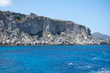 Trapani 'den tekne gezisi ve açık turkuvaz suyu, tuff kayaları, terk edilmiş taş ocakları, Sicilya, İtalya yakınlarındaki Egadi Adaları ile birlikte Favignana adasının kıyı şeridi manzarası.