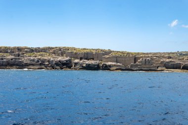 Trapani 'den tekne gezisi ve açık turkuvaz suyu, tuff kayaları, terk edilmiş taş ocakları, Sicilya, İtalya yakınlarındaki Egadi Adaları ile birlikte Favignana adasının kıyı şeridi manzarası.