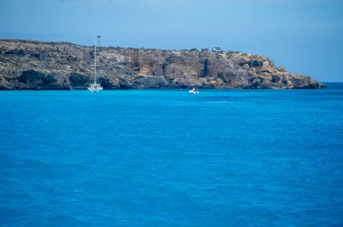 Trapani 'den tekne gezisi ve açık turkuvaz suyu, tuff kayaları, terk edilmiş taş ocakları, Sicilya, İtalya yakınlarındaki Egadi Adaları ile birlikte Favignana adasının kıyı şeridi manzarası.