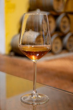 Eski büyük meşe fıçılarıyla şarap mahzenini ziyaret etmek, Marsala, Sicilya, İtalya ve şarap endüstrisindeki varillerden alınmış bir bardak güçlendirilmiş veya lezzetli marsala şarabı.