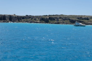 Trapani 'den tekne gezisi ve açık turkuvaz suyu, tuff kayaları, terk edilmiş taş ocakları, Sicilya, İtalya yakınlarındaki Egadi Adaları ile birlikte Favignana adasının kıyı şeridi manzarası.