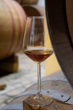 Eski büyük meşe fıçılarıyla şarap mahzenini ziyaret etmek, Marsala, Sicilya, İtalya ve şarap endüstrisindeki varillerden alınmış bir bardak güçlendirilmiş veya lezzetli marsala şarabı.