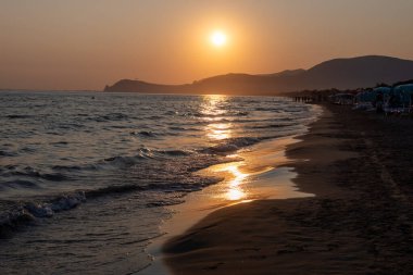 Güneş ışığında gün batımında yüzen insanların siluetleri, Sperlonga yakınlarındaki kumlu plajlar, Lazio, İtalya, yaz tatili
