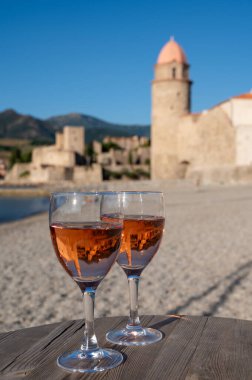 Eski Collioure kasabası manzaralı iki bardak gül Collioure AOC şarabı, renkli evler, kilise, kale ve plajlar, Occitanie, Fransa, turist beldesi