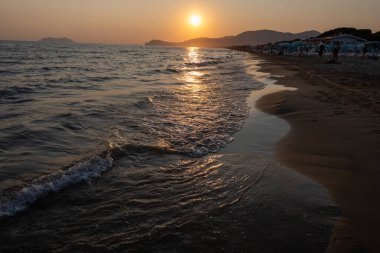Güneş ışığında gün batımında yüzen insanların siluetleri, Sperlonga yakınlarındaki kumlu plajlar, Lazio, İtalya, yaz tatili