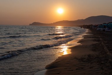 Güneş ışığında gün batımında yüzen insanların siluetleri, Sperlonga yakınlarındaki kumlu plajlar, Lazio, İtalya, yaz tatili
