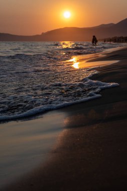 Güneş ışığında gün batımında yüzen insanların siluetleri, Sperlonga yakınlarındaki kumlu plajlar, Lazio, İtalya, yaz tatili