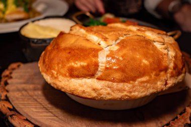 Biftek ve hakiki biralı turta, bol soslu yumuşak biftek, yumuşak hamur işiyle pişirilmiş kremalı krema püresi ve taze mevsim yeşillikleri, İngiltere 'de yiyecek.