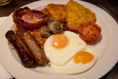 Yumurtalı tam İngiliz kahvaltısı, kızarmış pastırma, sosis, fasulye, tost, mantar, ızgara domates, klasik yemek, geleneksel İngiliz sabah yemeği.