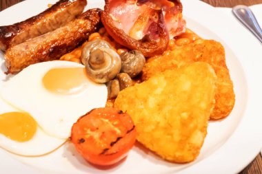 Yumurtalı tam İngiliz kahvaltısı, kızarmış pastırma, sosis, fasulye, tost, mantar, ızgara domates, klasik yemek, geleneksel İngiliz sabah yemeği.