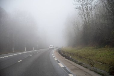 Yoğun siste araba sürmek görüş mesafesi düşük, tepelerde kış ormanı, yoğun sis ve nem, kış havası.
