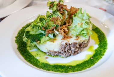 Şekerli ördek, patates püresi ve taze yeşil pesto karışımı Fransız yemeği Paris 'teki geleneksel bistro restoranında servis edilir.