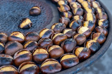 Geleneksel Fransız yemek ekipmanları ateşte taze kestane kızartır ve ızgara yapar. Lezzetli sokak yemekleri, sonbaharda Paris sokaklarında fındık yemek.