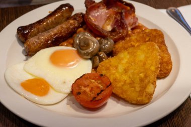 Yumurtalı tam İngiliz kahvaltısı, kızarmış pastırma, sosis, fasulye, tost, mantar, ızgara domates, klasik yemek, geleneksel İngiliz sabah yemeği.