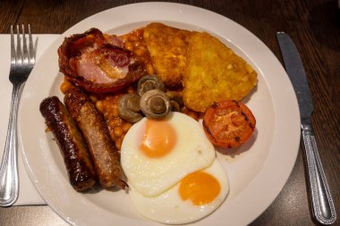 Yumurtalı tam İngiliz kahvaltısı, kızarmış pastırma, sosis, fasulye, tost, mantar, ızgara domates, klasik yemek, geleneksel İngiliz sabah yemeği.