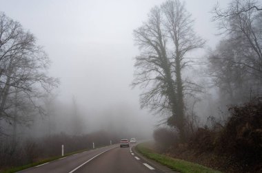 Yoğun siste araba sürmek görüş mesafesi düşük, tepelerde kış ormanı, yoğun sis ve nem, kış havası.
